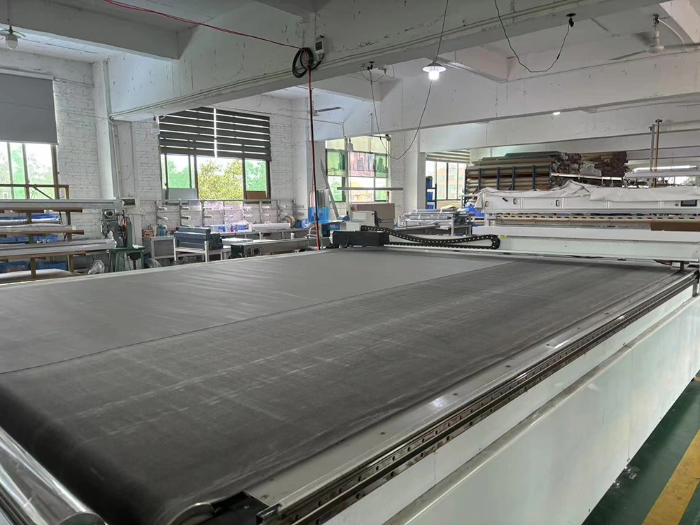 Wide-format outdoor mesh laid on a precision production table in a clean factory workshop.