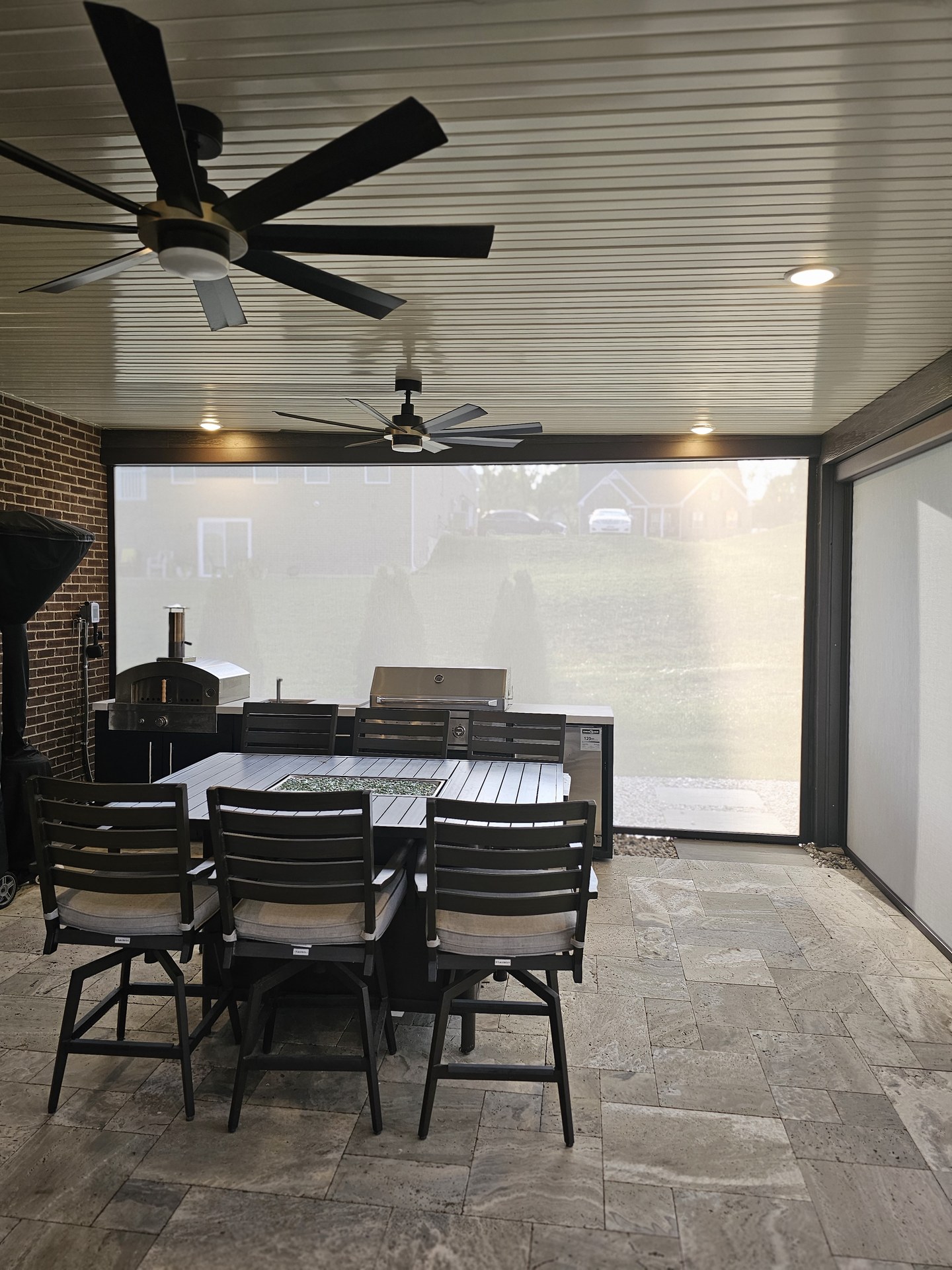 Outdoor dining table and kitchen seen through patio screens.