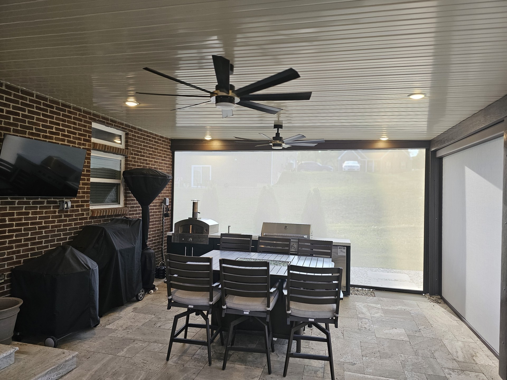 Furnished outdoor kitchen and dining room enclosed with patio screens.